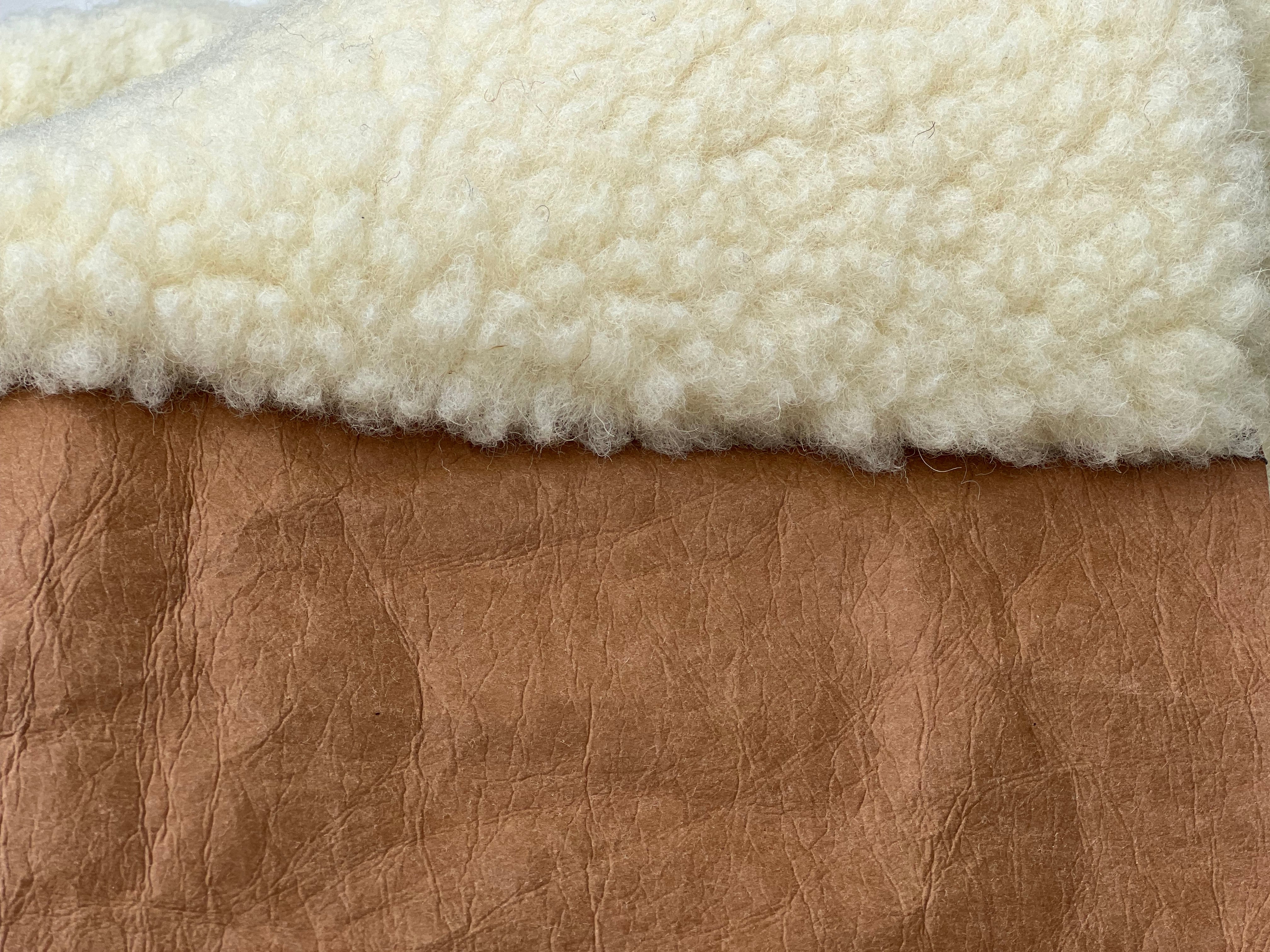 Detail Hundedecke für unterwegs: weiche Schafwolloberfläche trifft braunes, veganes Leder.